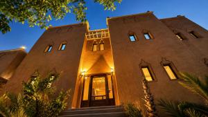 a large brick building with a front door at night at Riad Ouinz in Aït Benhaddou