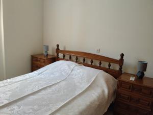 a bedroom with a white bed with two dressers and two lamps at Waves and Wonders Apartment in Korthi
