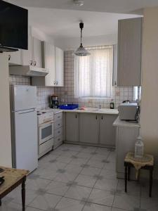 a kitchen with white cabinets and a white refrigerator at Waves and Wonders Apartment in Korthi