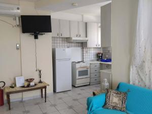 a kitchen with a white refrigerator and a blue couch at Waves and Wonders Apartment in Korthi