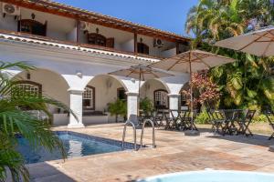 a patio with tables and umbrellas next to a pool at Pousada Boulevard in Cabo Frio