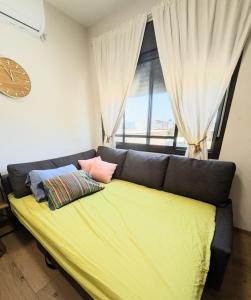 a large yellow bed with pillows in a room with a window at Noy Hosting in the Golan in Nov