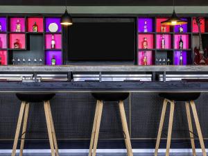 a bar with two stools in front of a television at Ibis Styles Merida Galerias in Mérida