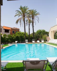 a large swimming pool with chairs and palm trees at Oro Hotel in Policoro