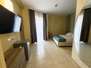 a hotel room with a bed and a flat screen tv at Oro Hotel in Policoro