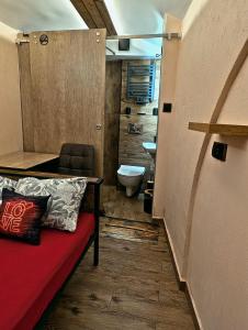a bathroom with a red couch and a toilet at Podziemne Arkady-nocleg centrum blisko dworca in Gniezno