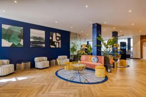 a living room with a couch and a table and chairs at voco Gent by IHG in Ghent