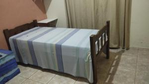 a bed with a blue and white striped blanket on it at Casa cantinho da Rubi in Atibaia