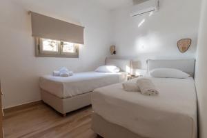 two beds in a white room with a window at Casa del mare in Pyrgos