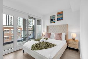 a white bedroom with a large bed and a window at Filmos Hotel and Suites in Toronto