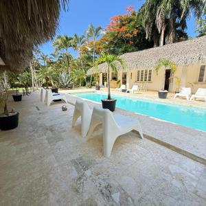 a pool with white benches next to a building at Terra Taina Boutique Bed&Breakfast in Las Terrenas