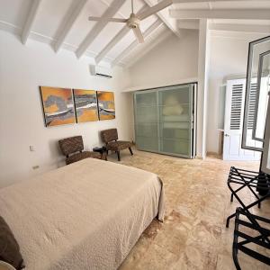 a bedroom with a bed and two chairs and a window at Terra Taina Boutique Bed&Breakfast in Las Terrenas