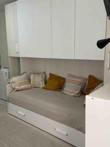 a bed in a room with white cabinets and pillows at Studio apartment on the lake in Lovere
