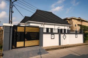 a white building with two garage doors with a black roof at Seychelles Bella House in Mahe
