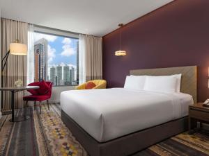 a hotel room with a large white bed and a window at Mercure Bangkok Sukhumvit 24 in Bangkok