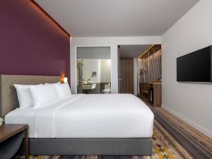 a hotel room with a large bed and a tv at Mercure Bangkok Sukhumvit 24 in Bangkok