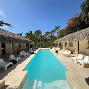 a pool at a resort with chairs and umbrellas at Terra Taina Boutique Bed&Breakfast in Las Terrenas