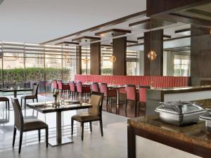 a restaurant with tables and chairs and a bar at Mövenpick Hotel Apartments Al Mamzar Dubai in Dubai