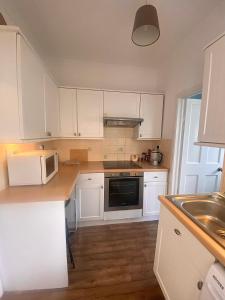 a kitchen with white cabinets and a sink at The Nest Chelmsford in Chelmsford
