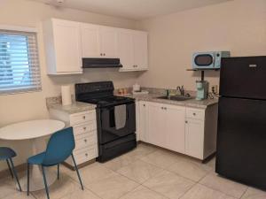 a kitchen with white cabinets and a black refrigerator at Queen's Court Inn in Saint Simons Island