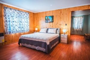 a bedroom with a bed and wooden walls and wood floors at Hotel Iorana Tolache in San Pedro de Atacama