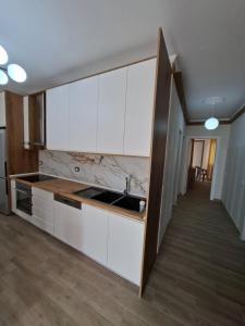 a kitchen with white cabinets and a sink at Rafaelo Apartament in Lezhë