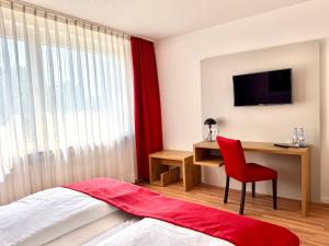 a bedroom with a bed and a desk with a red chair at Stadthotel Langenfeld in Langenfeld