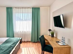 a bedroom with a desk and a bed with green curtains at Stadthotel Langenfeld in Langenfeld +10 photos