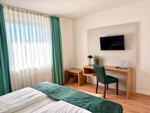 a bedroom with a bed and a desk with a chair at Stadthotel Langenfeld in Langenfeld