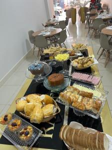 a table with many different types of pastries on it at Rafa Plaza Hotel in Cassilândia