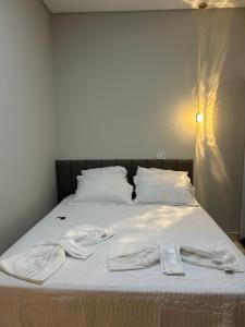 a bed with white sheets and a robe on it at Rafa Plaza Hotel in Cassilândia