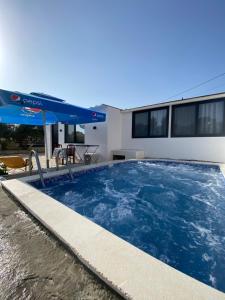 a large swimming pool with an umbrella next to a house at Luciano Rooms in Ksamil