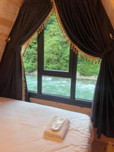 a bed in a room with a large window at Elegant Residence in Çamlıhemşin