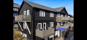 a black house with balconies and a blue arrow at Oppdal Alpintun in Oppdal +8 photos