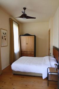 a bedroom with a white bed and a ceiling fan at Racha Roots Boutique House in Ambrolauri