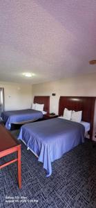 two beds in a hotel room with blue sheets at Red Carpet Inn Williamstown in Williamstown