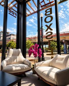 two white leather couches in a building with a large window at Boxstel - Modern Stay Hotel Downtown El Paso in El Paso
