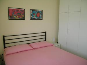 a bedroom with a pink bed with two pictures on the wall at Casa Costaverde in Mandatoriccio Marina