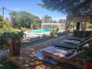 a deck with four pillows and a swimming pool at Mas des 2 paons in Villedaigne