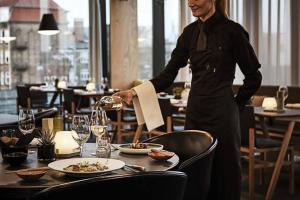 a woman is setting a table in a restaurant at Comwell in Odense