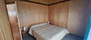 a bedroom with a bed in a wooden wall at Cabañas Llifén Costanera in llifen +4 photos