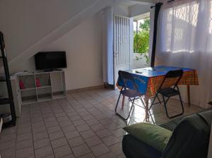 a living room with a table and chairs and a tv at Marilou in Basse-Terre
