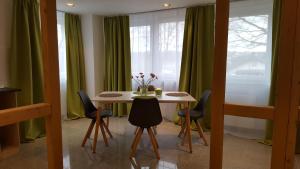 comedor con mesa y cortinas verdes en Gästeappartements Bierfässl, en Sinsheim