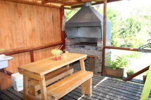 a wooden bench sitting on a deck with a grill at Cabañas Alfa Colbun Machicura in Linares
