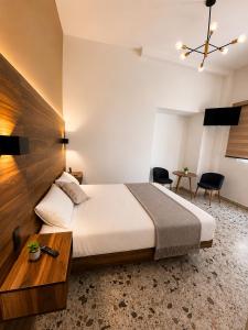 a bedroom with a large bed and a table at Hotel Queretaro in Querétaro