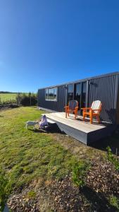 a person sitting on a deck next to a house at Frogs Hollow in Greytown