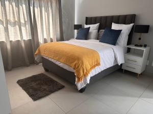 a bedroom with a large bed with blue pillows at Nova Apartments- MbabaneCBD in Mbabane