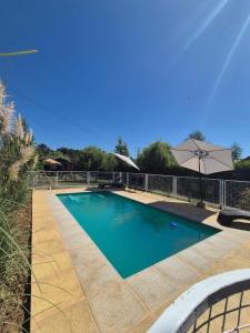a swimming pool with a fence and an umbrella at Cabañas Alfa Colbun Machicura in Linares