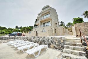 a group of white lounge chairs in front of a building at Leut Apartments in Tivat