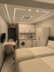 a room with two beds and a kitchen with tables and chairs at Vizyon Konak in Burhaniye